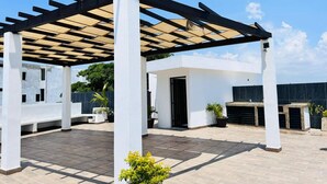 Eine Dachterrasse mit einer Pergola, Kübelpflanzen und einer kleinen Außenküche.