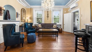 A spacious living room with a chandelier, leather armchair, sofa, ottoman, and a coffee table. - Stay in Historic Bucks County Farmhouse
Sleeps 18 -13 beds, 5 baths, 2 kitchens  (Bensalem)