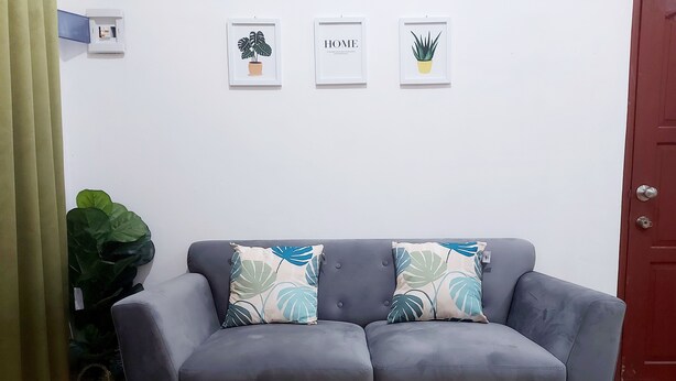 Ein graues Sofa mit zwei Zierkissen, einem kleinen Tisch und einem Blumentopf.