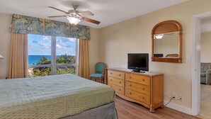 A bedroom with a bed, a dresser, a television, and a view of the ocean. - Prime Central Beach Location! 1BR OCeanfront, Pool, Bar, Game Room, at Fort Lauderdale Beach Resort (Fort Lauderdale)