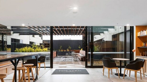 A modern indoor space with a glass wall leading to an outdoor seating area. - Artistic Getaway by Artist Abodes (Fitzroy)