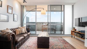 Una sala de estar moderna con un sofá de cuero, una mesa de centro y un amplio ventanal con vistas a un balcón.