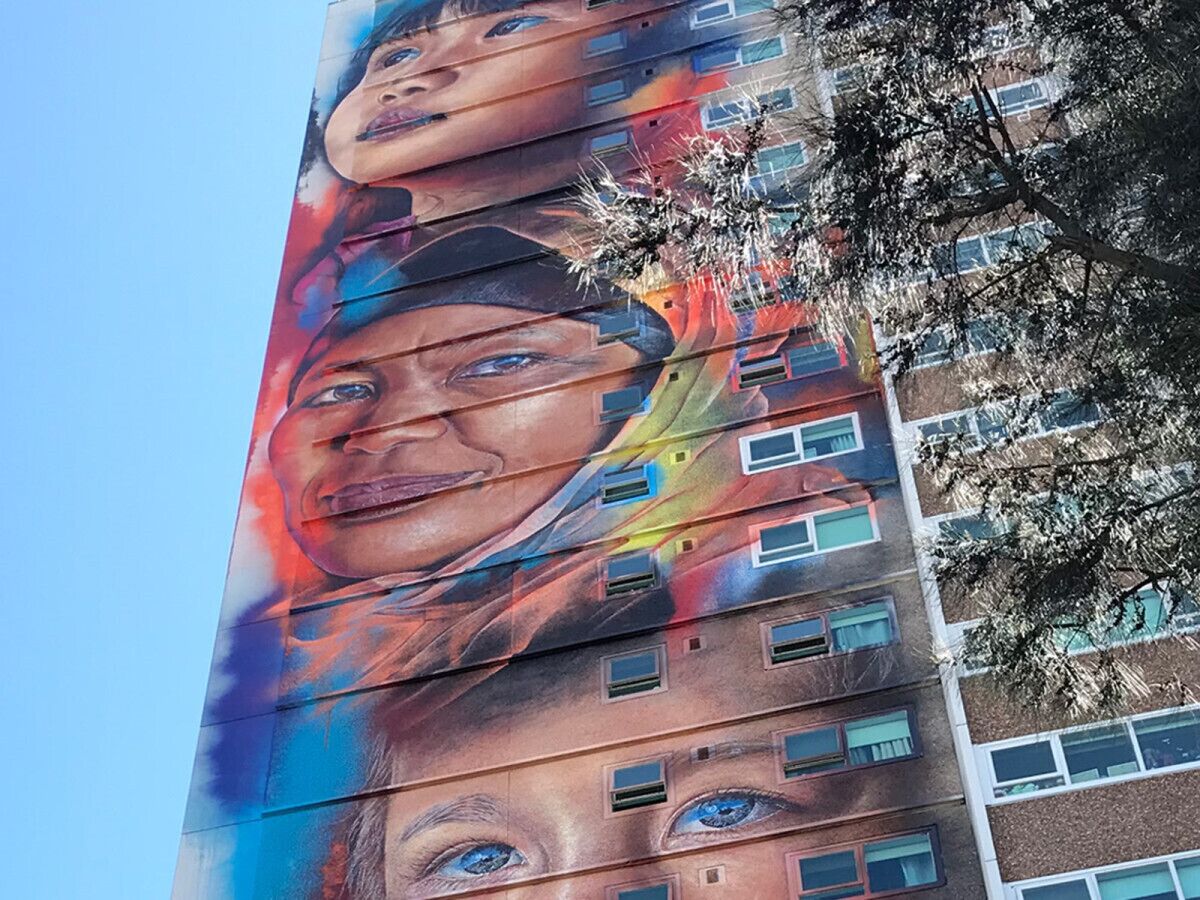 A building with a large mural featuring multiple faces.