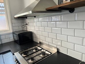 Uma cozinha com azulejos brancos tipo metrô, uma torradeira preta e um fogão de aço inoxidável.