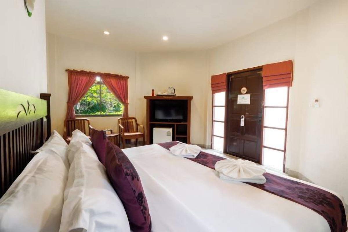 A hotel room with a bed, a desk, a television, and a window with curtains.