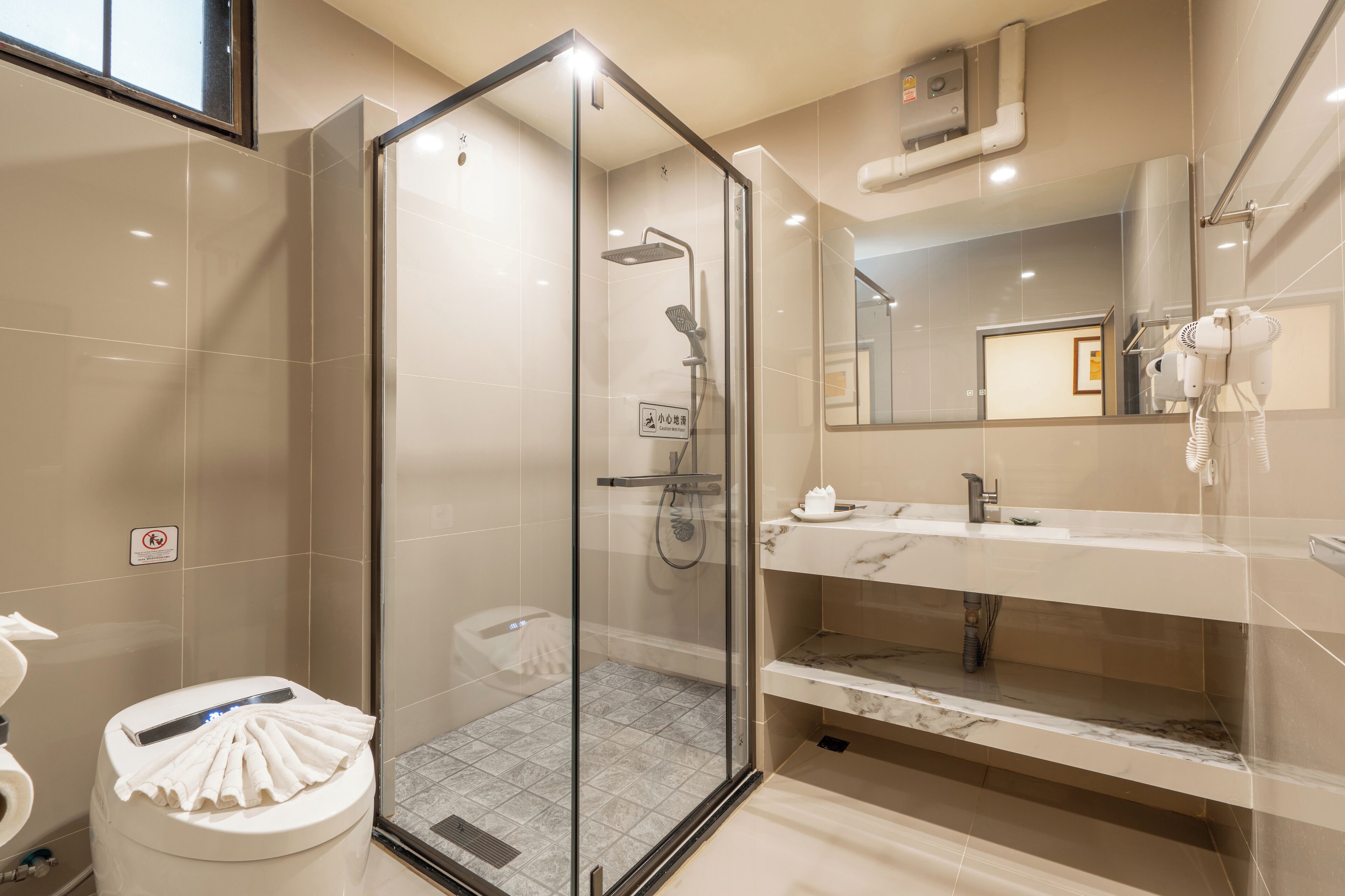 A modern bathroom with a glass-enclosed shower, a white toilet, and a marble-tiled vanity with a mirror.