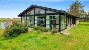 A modern house with large glass windows, a flat roof, and a well-maintained lawn.