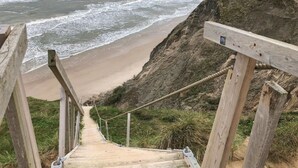 A wooden staircase leading down to a beach with waves crashing onto the shore.