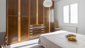 A bedroom with a large wardrobe, a bed with a white bedspread, and a window with blinds. - Apartment Maria by Interhome (Sanremo)