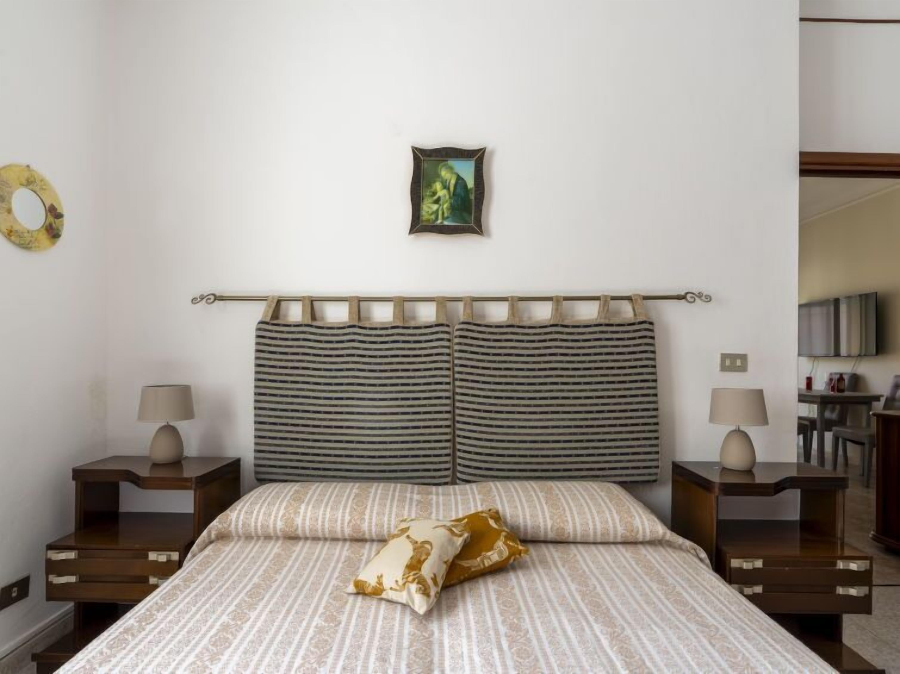 A neatly arranged bedroom with a bed, two bedside tables, and a small wall-mounted picture.