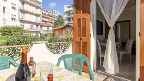 A balcony with a table set for two, a bottle of wine, and a glass. The balcony overlooks a residential area with multiple buildings. - Apartment Maria by Interhome (Sanremo)