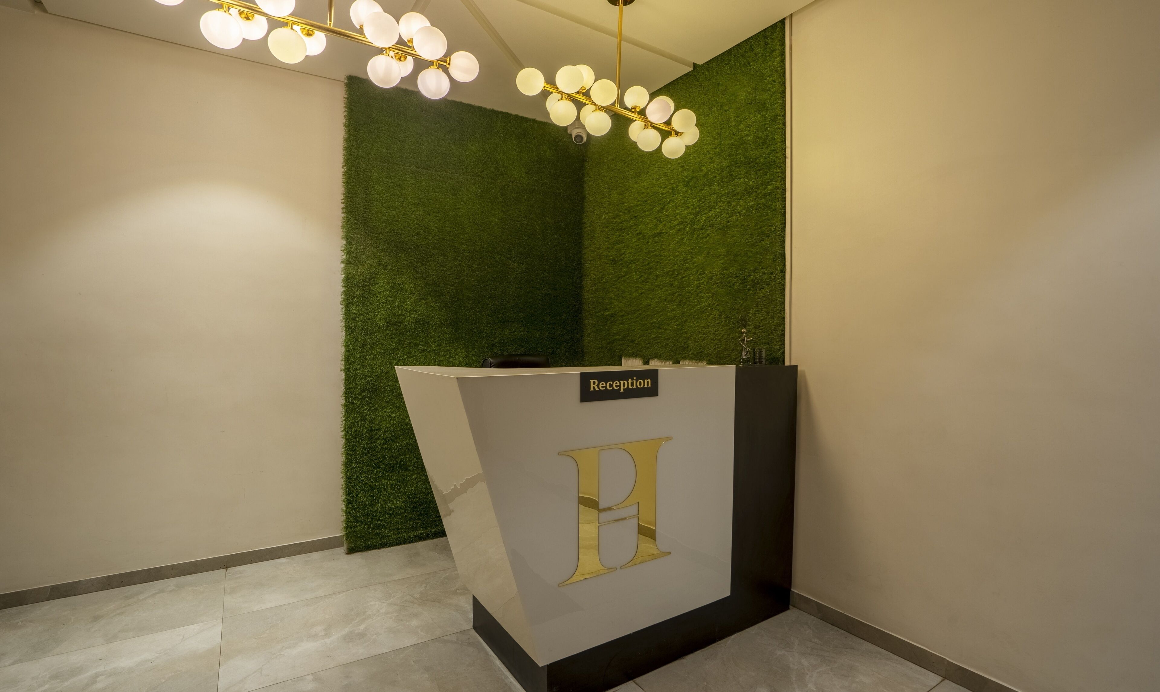Un área de recepción con mostrador, pared verde y lámpara en el techo.