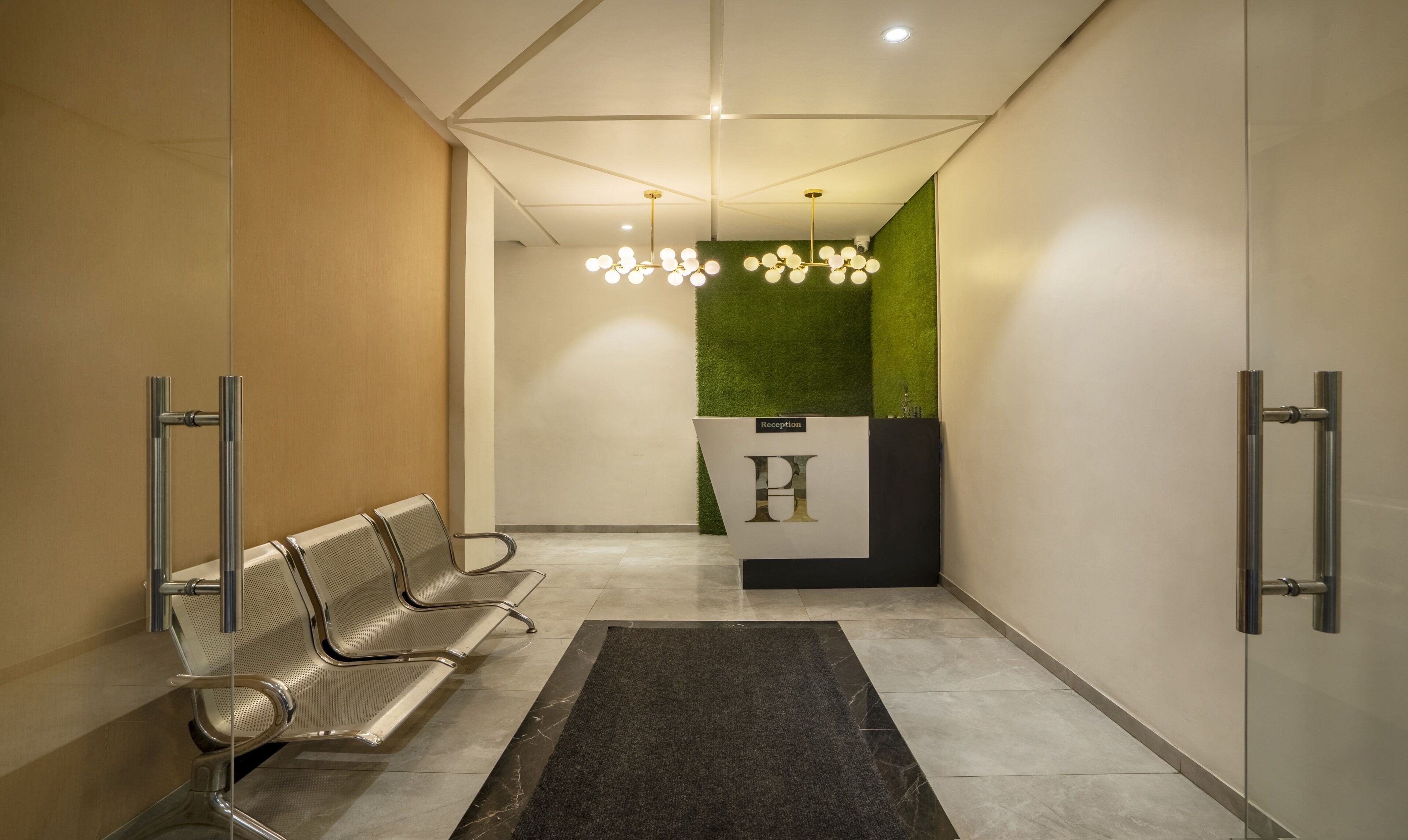 A reception area with a reception desk, a green wall, and a chandelier.