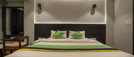 Ein Hotelzimmer mit Bett, Nachttisch, Stuhl und Spiegel.