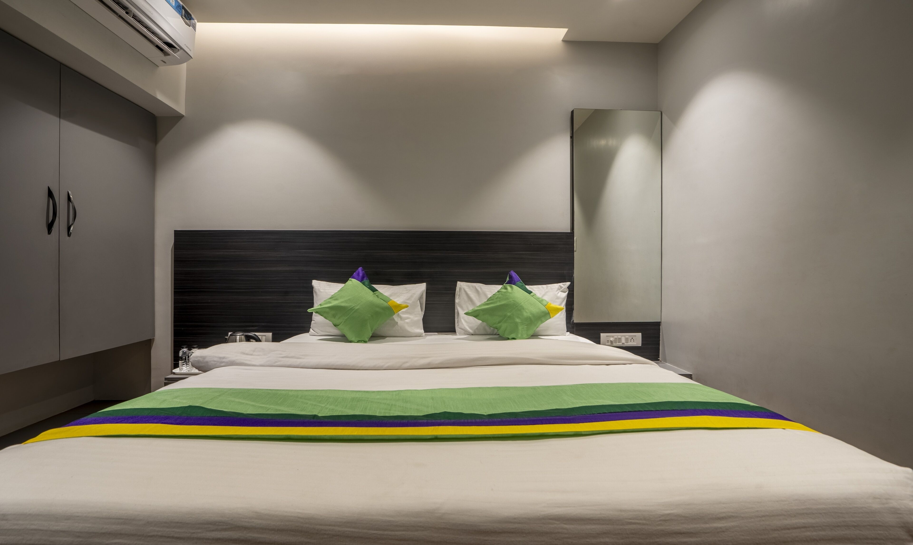 Une chambre d’hôtel moderne avec un grand lit, une tête de lit sombre et un téléviseur à écran plat.
