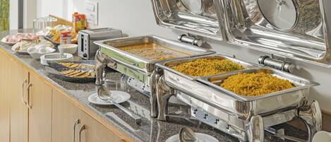 A breakfast buffet with various food options and utensils.