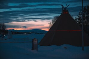 A snow-covered landscape with a tipi and a sign in the foreground. - AERA - Aurora Glass Cabins (Tromsø)