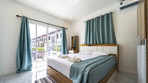 A modern bedroom with a large bed, a sliding glass door to a balcony, and an air conditioning unit on the wall. - 4 Bedroom Private Pool Villa - OV10 (Hua Hin)