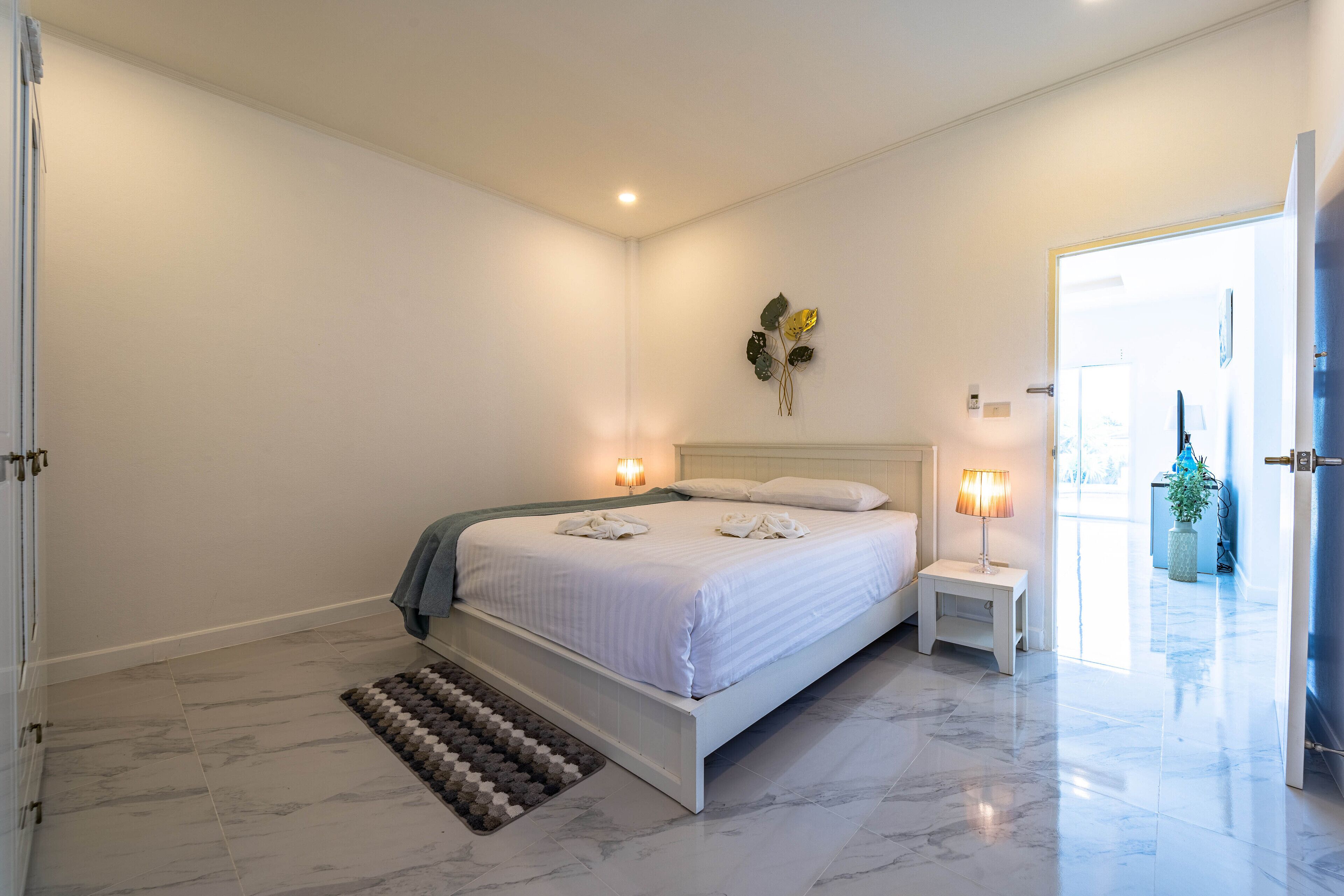 A modern bedroom with a large bed, bedside lamps, and a view of the outside.