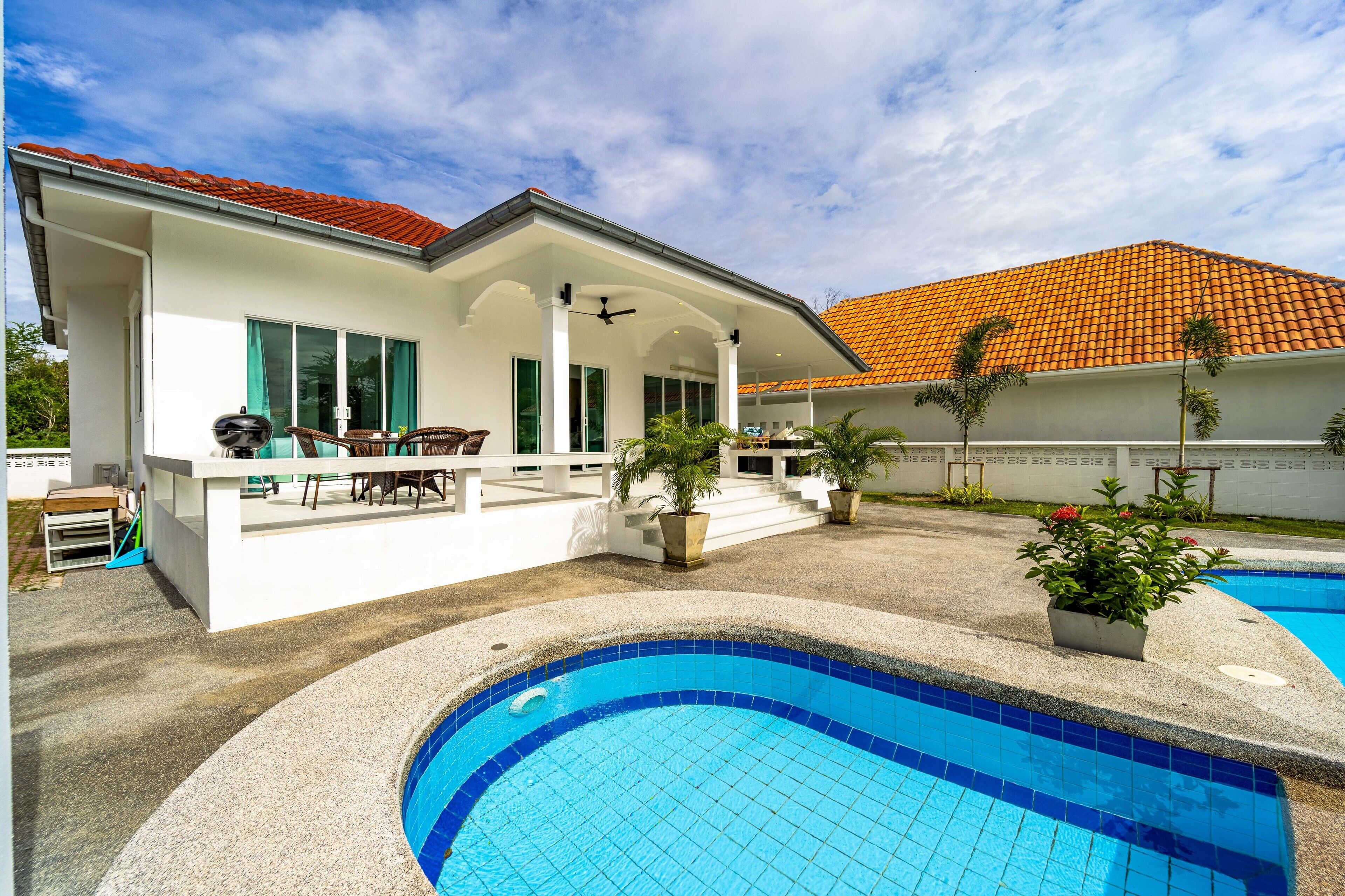 Une maison moderne dotée d’une piscine, d’un espace salon extérieur et d’un patio couvert.