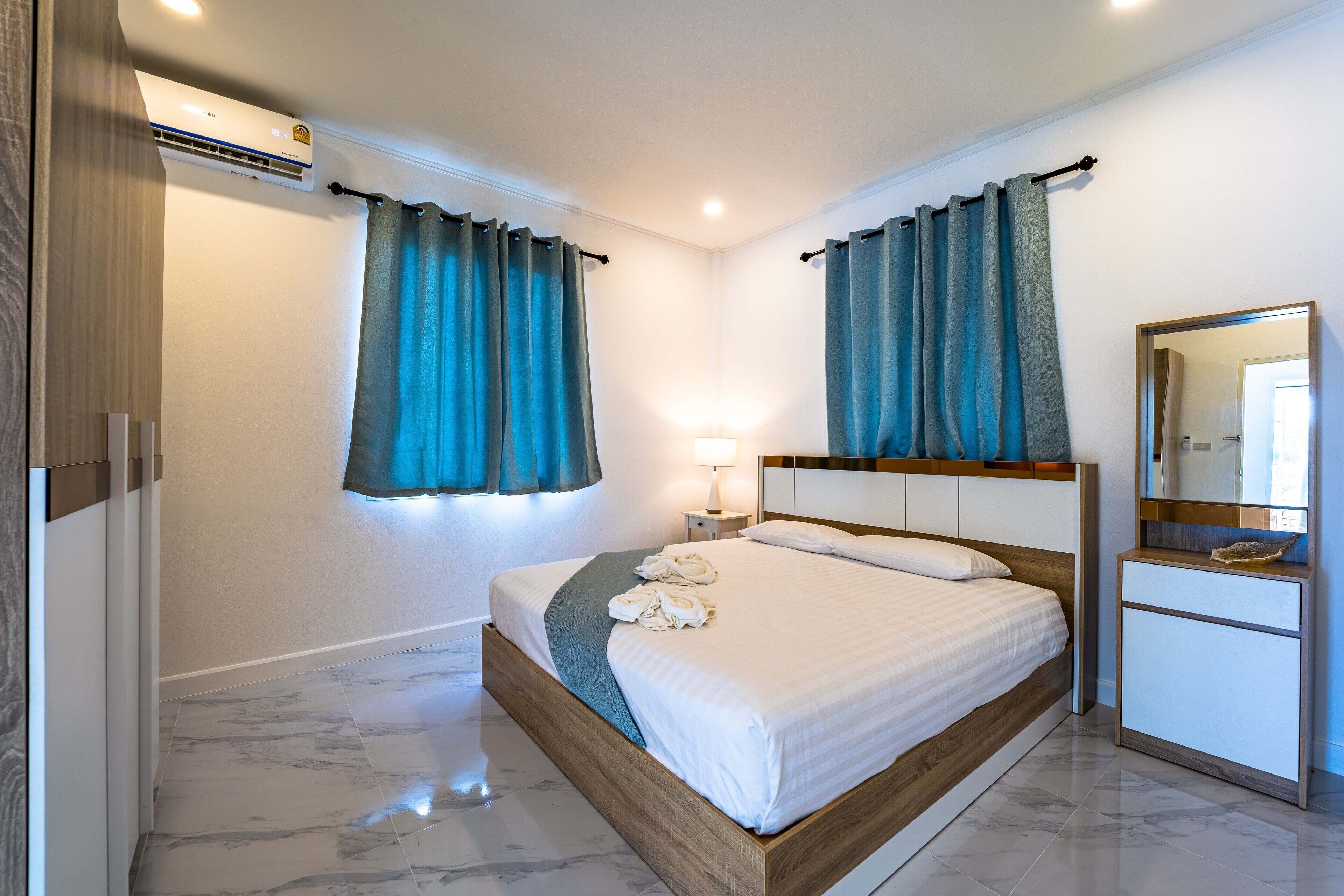 A modern bedroom with a wooden bed frame, a bedside table with a lamp, and a mirror.