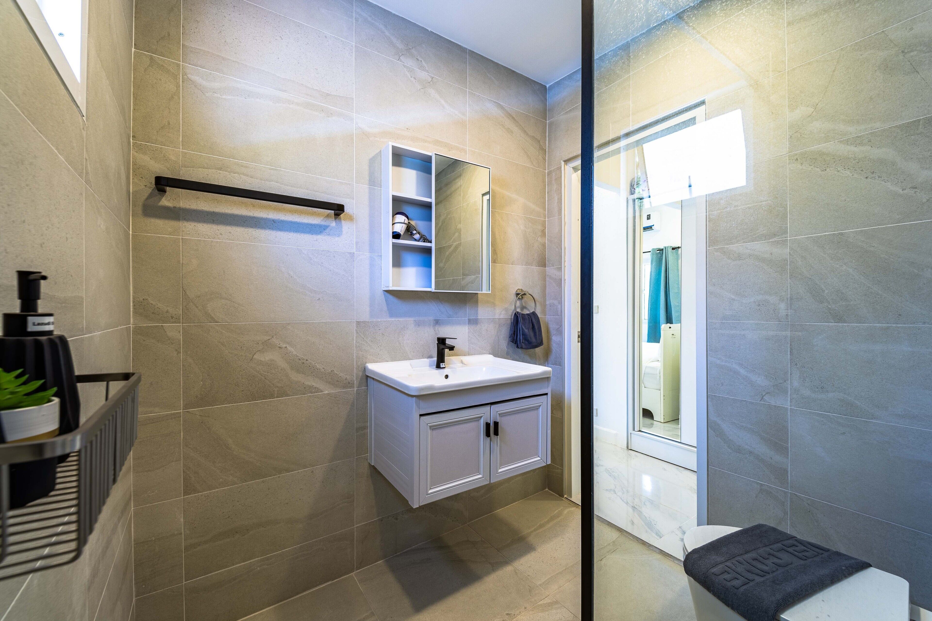 Een moderne badkamer met een wit wastafelmeubel, een spiegel en een handdoekrek.