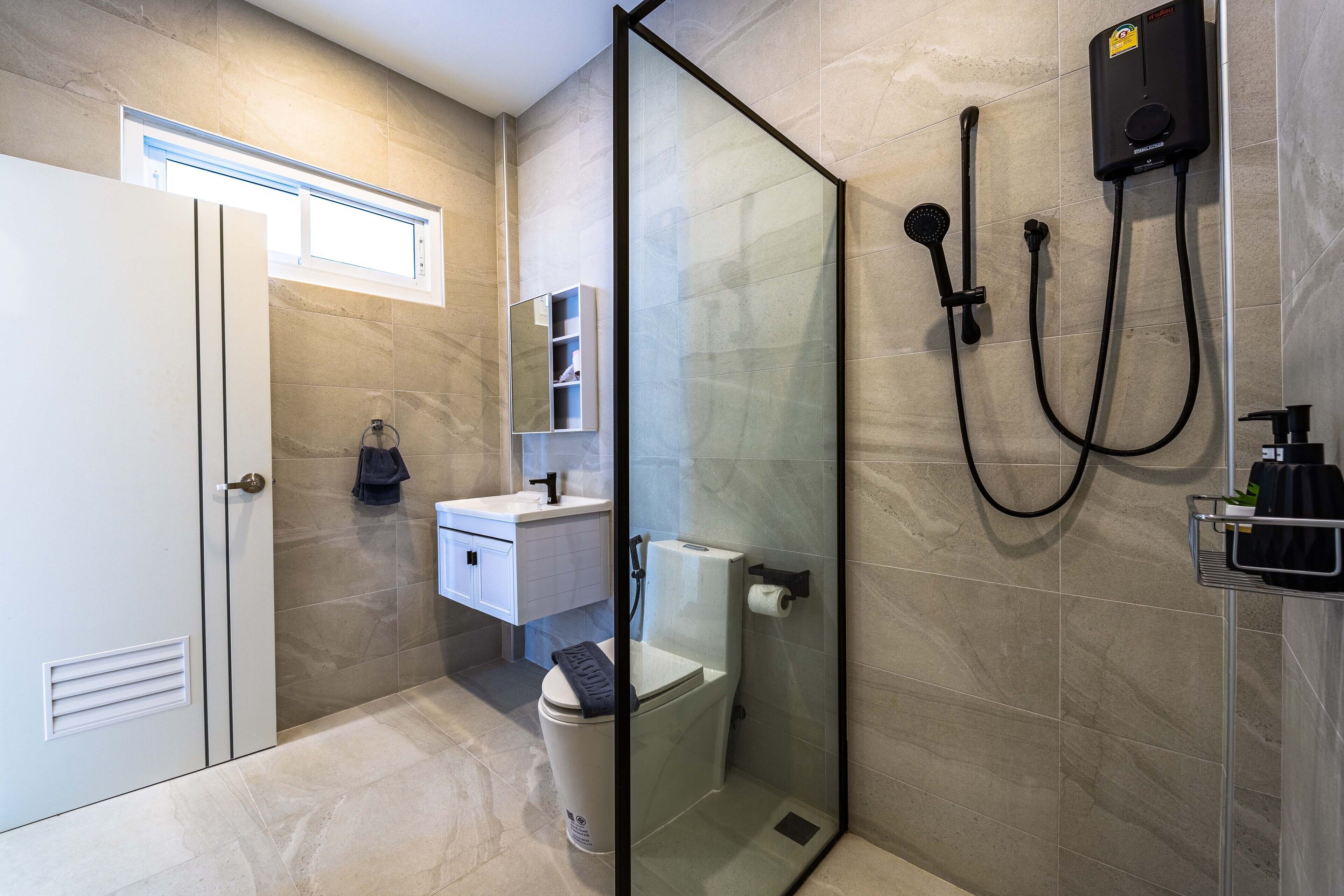 A modern bathroom with a glass-enclosed shower, a toilet, and a sink.