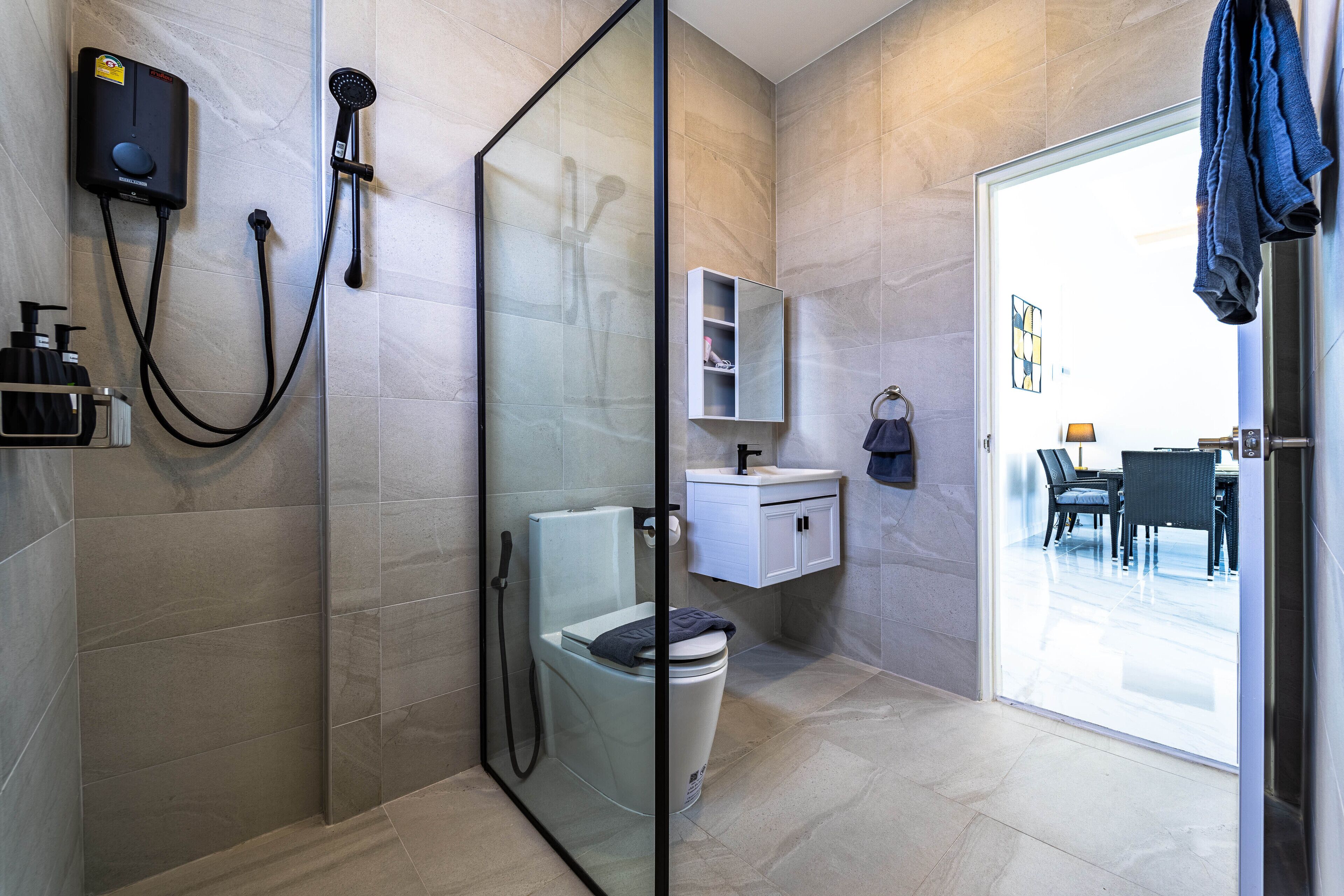 Un baño moderno con cabina de ducha de vidrio, inodoro y lavabo con espejo superior.
