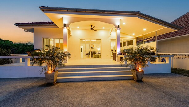 A modern house with a covered entrance, large windows, and potted plants. - 4 Bedroom Private Pool Villa - OV10 (Hua Hin)