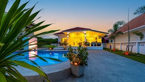 A modern house with a swimming pool, a covered patio, and a well-maintained garden. - 4 Bedroom Private Pool Villa - OV10 (Hua Hin)