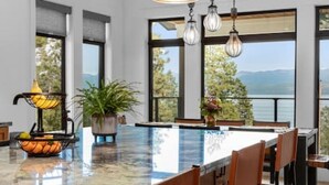 A kitchen with a large island, bar stools, pendant lights, and a view of the outdoors. - Luxury Lakeside Retreat w/ Panoramic Flathead View (Lakeside)
