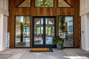 A wooden exterior with large glass doors, a welcome mat, and a sign. - Luxury Lakeside Retreat w/ Panoramic Flathead View (Lakeside)