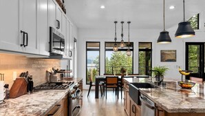 A modern kitchen with a central island, stainless steel appliances, and large windows offering a view of the outdoors. - Luxury Lakeside Retreat w/ Panoramic Flathead View (Lakeside)