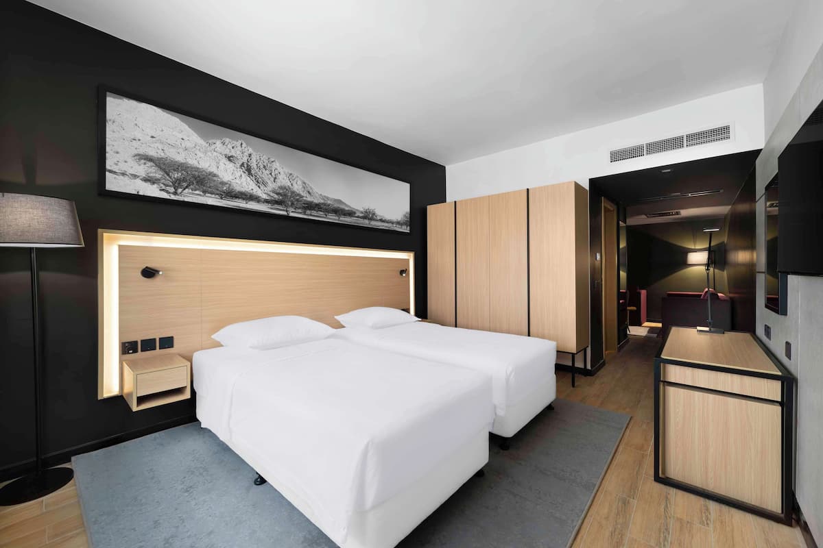 A modern hotel room with a large bed, bedside tables, a desk, and a TV.
