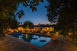 A swimming pool surrounded by a patio area with lounge chairs and umbrellas. - Prakriti The Nature Resort Pushkar (Pushkar)