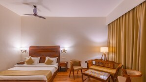 A hotel room with a wooden bed, a wooden sofa, a wooden coffee table, and a ceiling fan. - Prakriti The Nature Resort Pushkar (Pushkar)