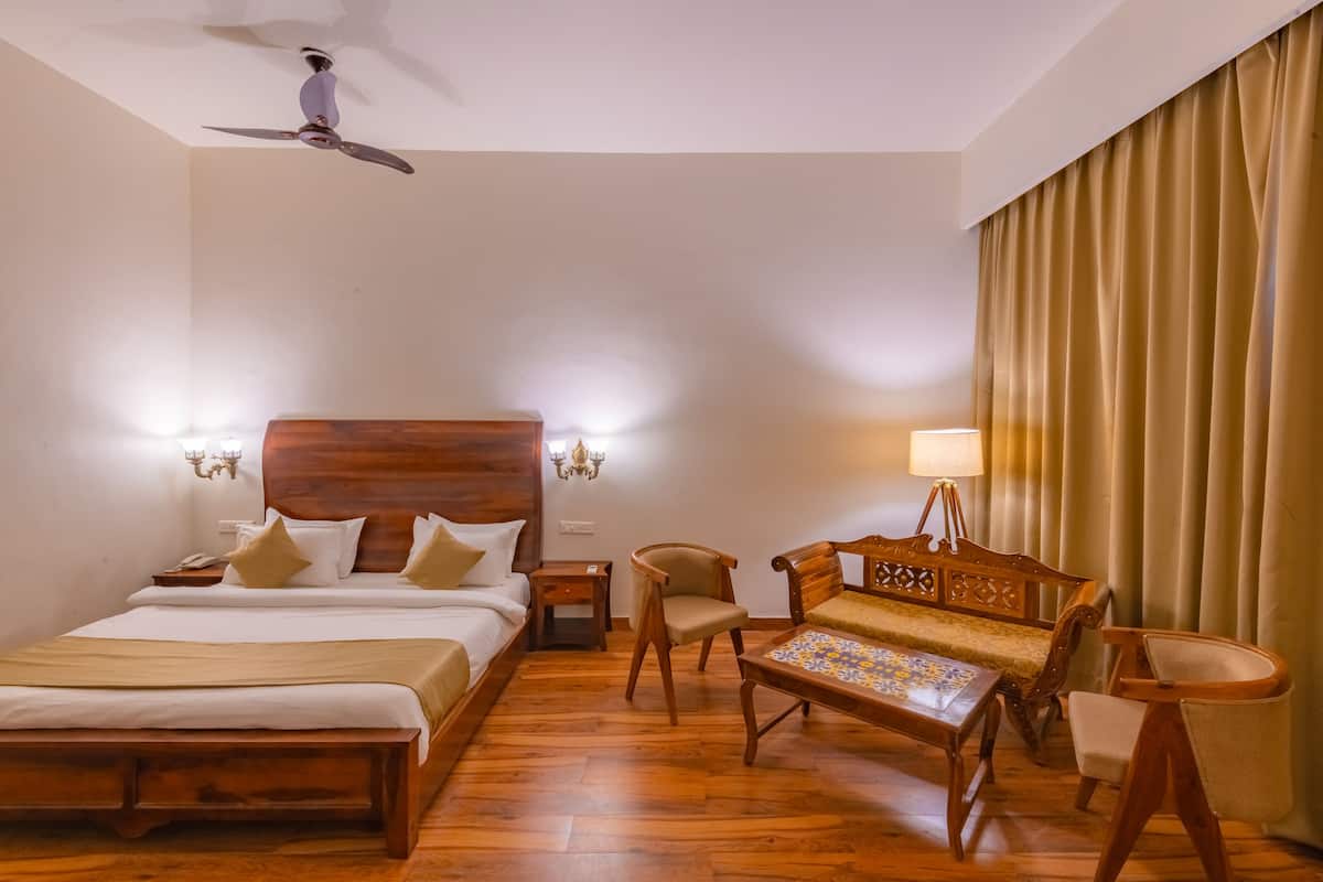 A hotel room with a wooden bed, a wooden sofa, a wooden coffee table, and a ceiling fan.