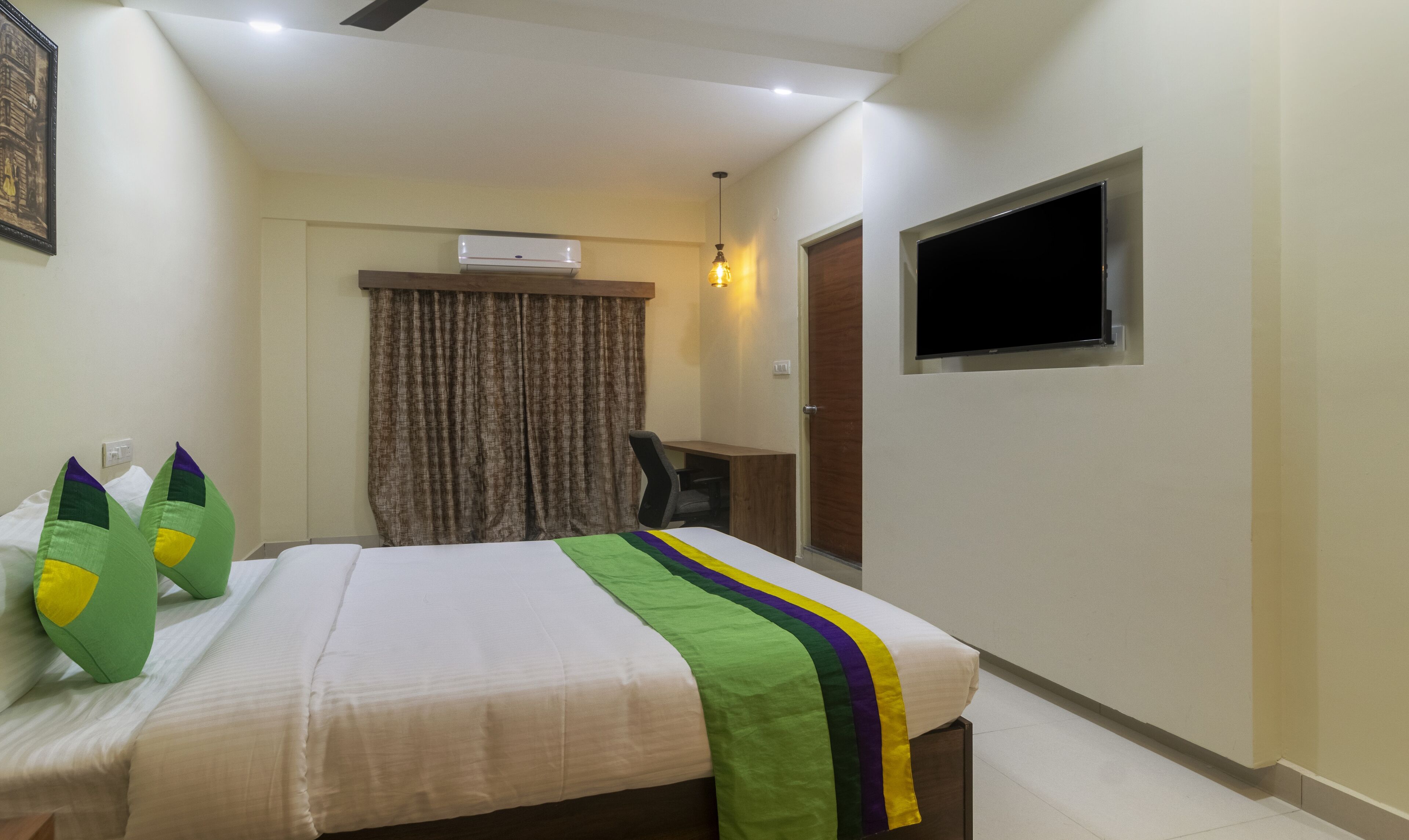 A hotel room with a bed, a desk, a chair, a TV, and a window.