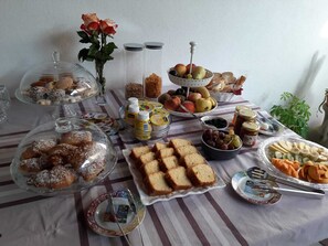 Una mesa de buffet con diferentes opciones de comida, como pasteles, pan, frutas y salsas.