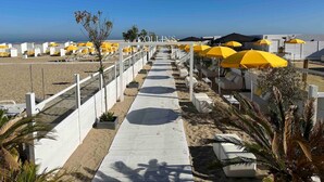 A beachside hotel with a walkway lined with yellow umbrellas and white lounge chairs. - Luxurious 5-Bedroom Holiday House in Knokke-Heist Belgique (Knokke-Heist)