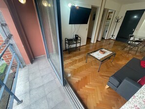 Una sala de estar moderna con una televisión de pantalla plana, una mesa de centro de vidrio y un sofá gris.