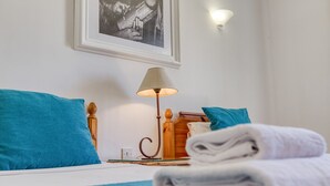 A neatly made bed with blue bedding, a lamp, and a folded towel on the side. - Ta Frenc Apartments - 2 BDR, 2 BTH (L-Għasri)