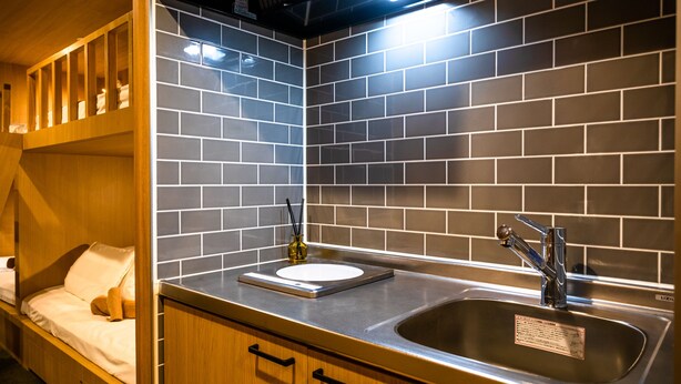 Una cocina compacta con un lavamanos integrado, armarios de madera y un pequeño banco con cojín.