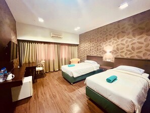 Quarto de hotel com duas camas, uma escrivaninha, uma cadeira, uma televisão e parede com padrão.