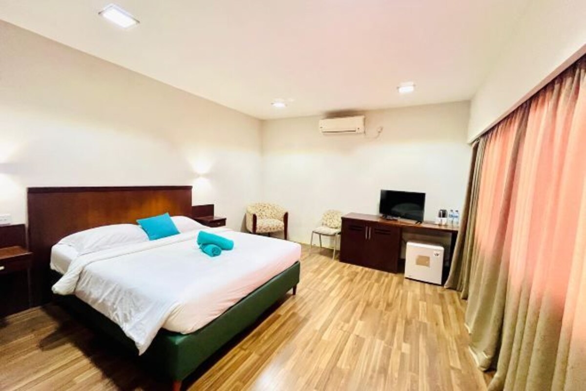 Ein Hotelzimmer mit Bett, Schreibtisch, Stuhl und Fernseher.