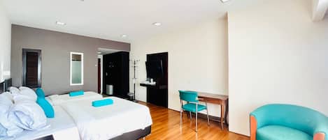 A modern hotel room with a large bed, a desk, a chair, and a television.