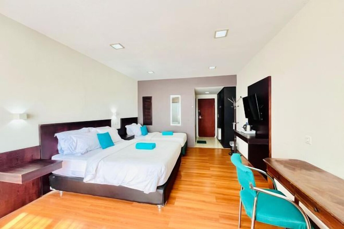 Ein Hotelzimmer mit einem großen Bett, einem Schreibtisch, einem Sessel und einem Fernseher.