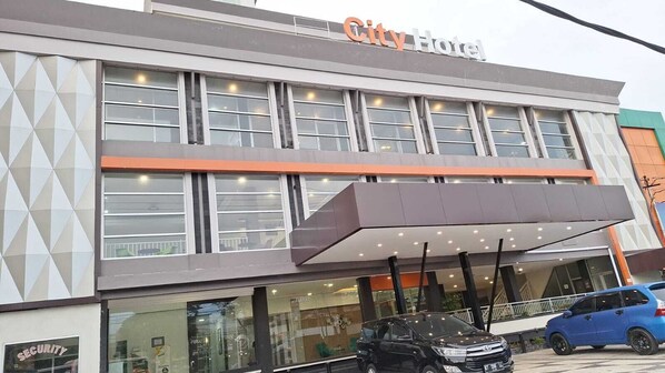 Um hotel urbano com fachada moderna, amplas janelas e área de entrada coberta.