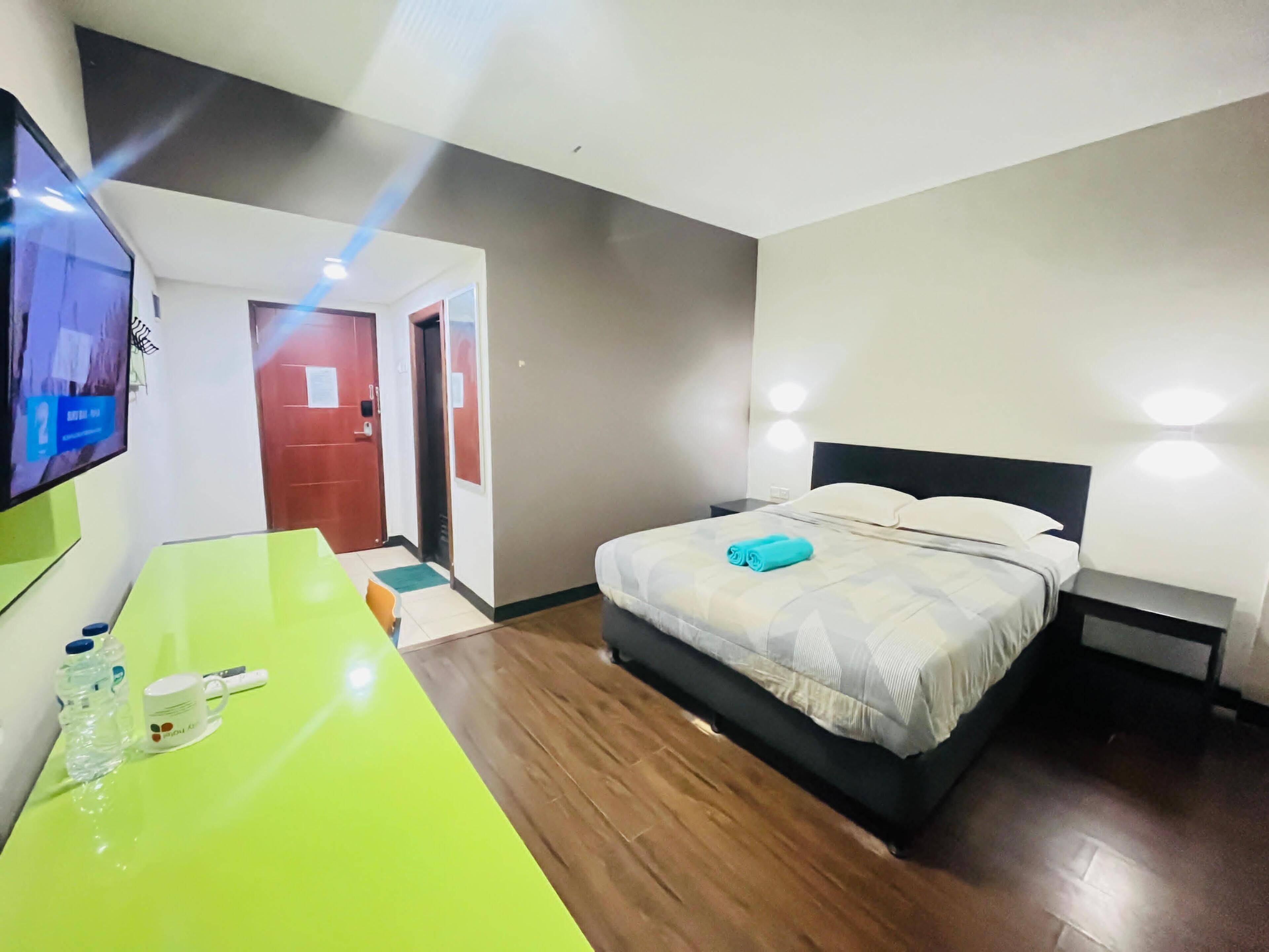 Una habitación de hotel con cama, mesita de noche y televisor en la pared.