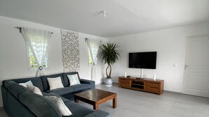 Ein modernes Wohnzimmer mit Sofa, Couchtisch, Fernseher und einem Blumentopf.
